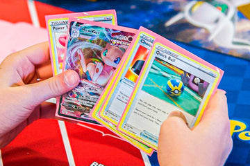 Hands holding colorful trading cards over a red 'Bench' area, with a blue mat in the background.
